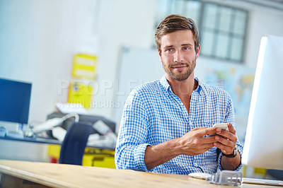 Buy stock photo Portrait of a designer using a cellphone while working on a computer in an office
