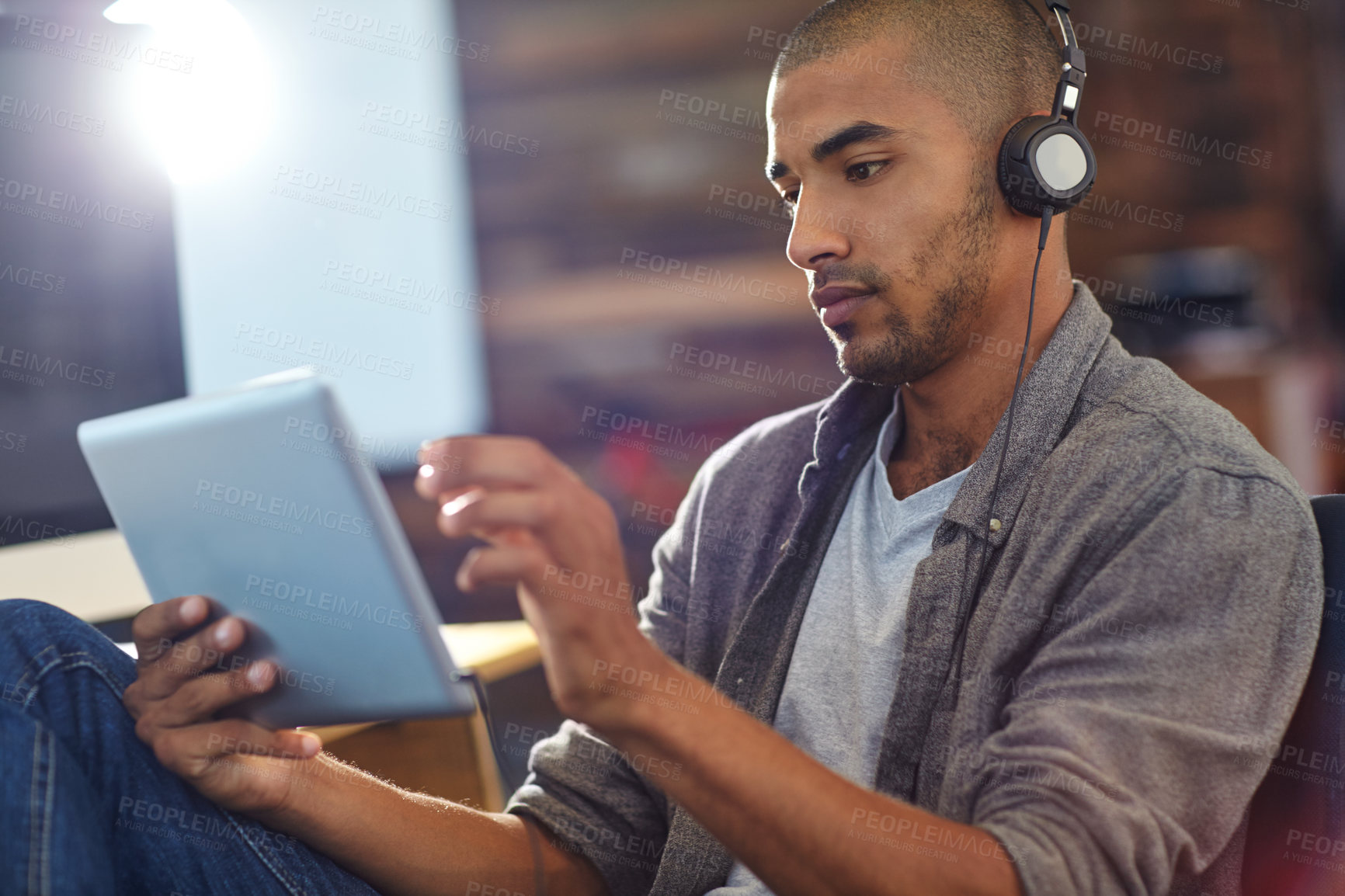 Buy stock photo Shot of a designer listening to music on a digital tablet in an office