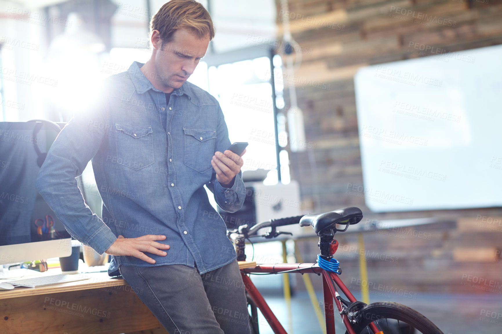 Buy stock photo Shot of designer using a cellphone while at work in an office