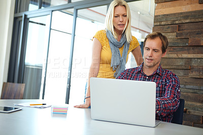 Buy stock photo Shot of two designers working on a laptop in an office