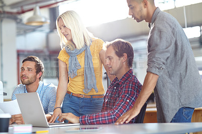 Buy stock photo Shot of a diverse group of designers working on a laptop in an office