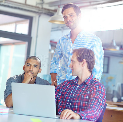 Buy stock photo Shot of a diverse group of designers working on a laptop in an office