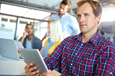 Buy stock photo Shot of a designer using a digital tablet with colleagues in the background