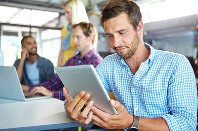 Buy stock photo Shot of a designer using a digital tablet with colleagues in the background