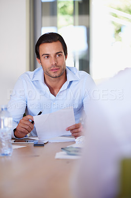 Buy stock photo Shot of a businessman holding a document while sitting in a meeting with colleagues