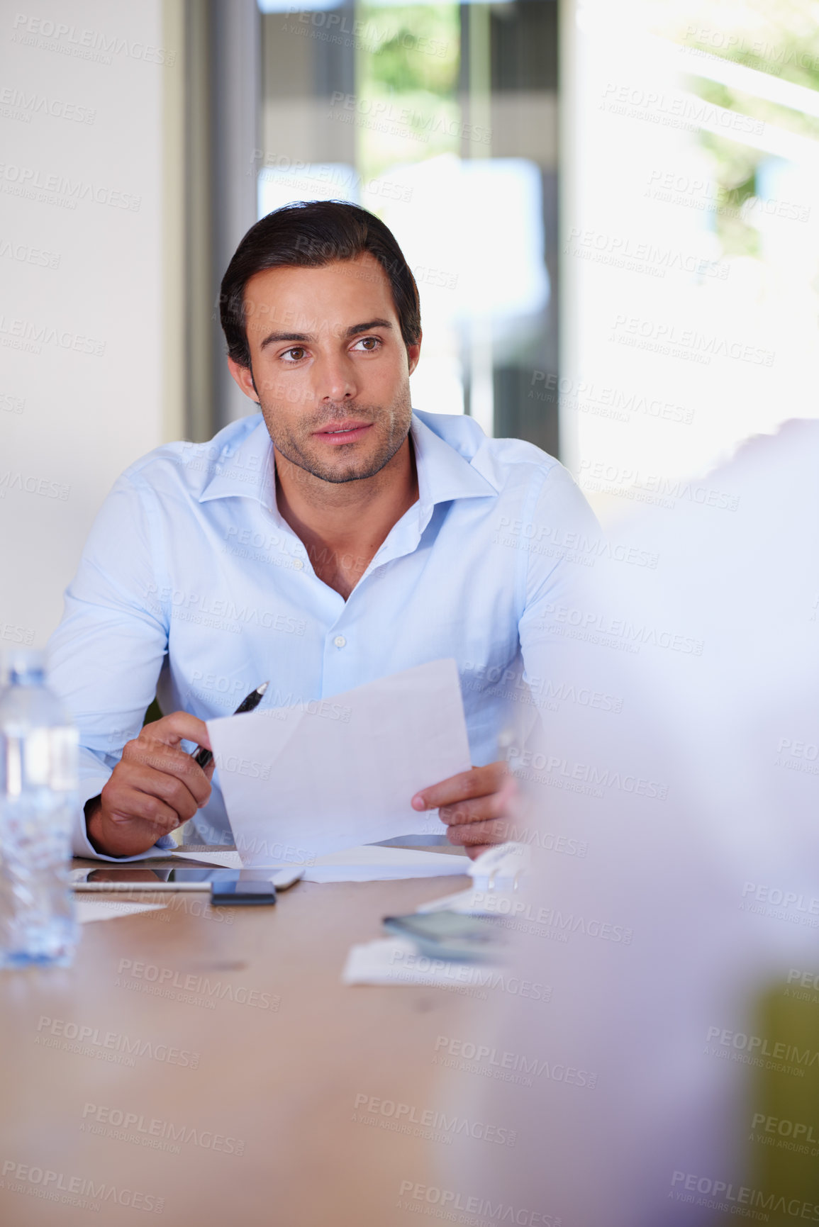 Buy stock photo Shot of a businessman holding a document while sitting in a meeting with colleagues