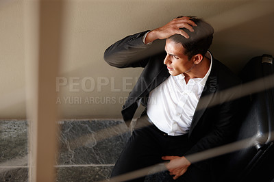 Buy stock photo Shot of an exhausted young businessman sitting on the floor beside his luggage