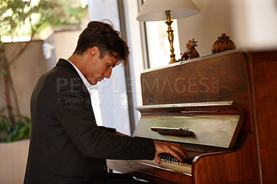 Buy stock photo Shot of a handsome young man playing the piano at home