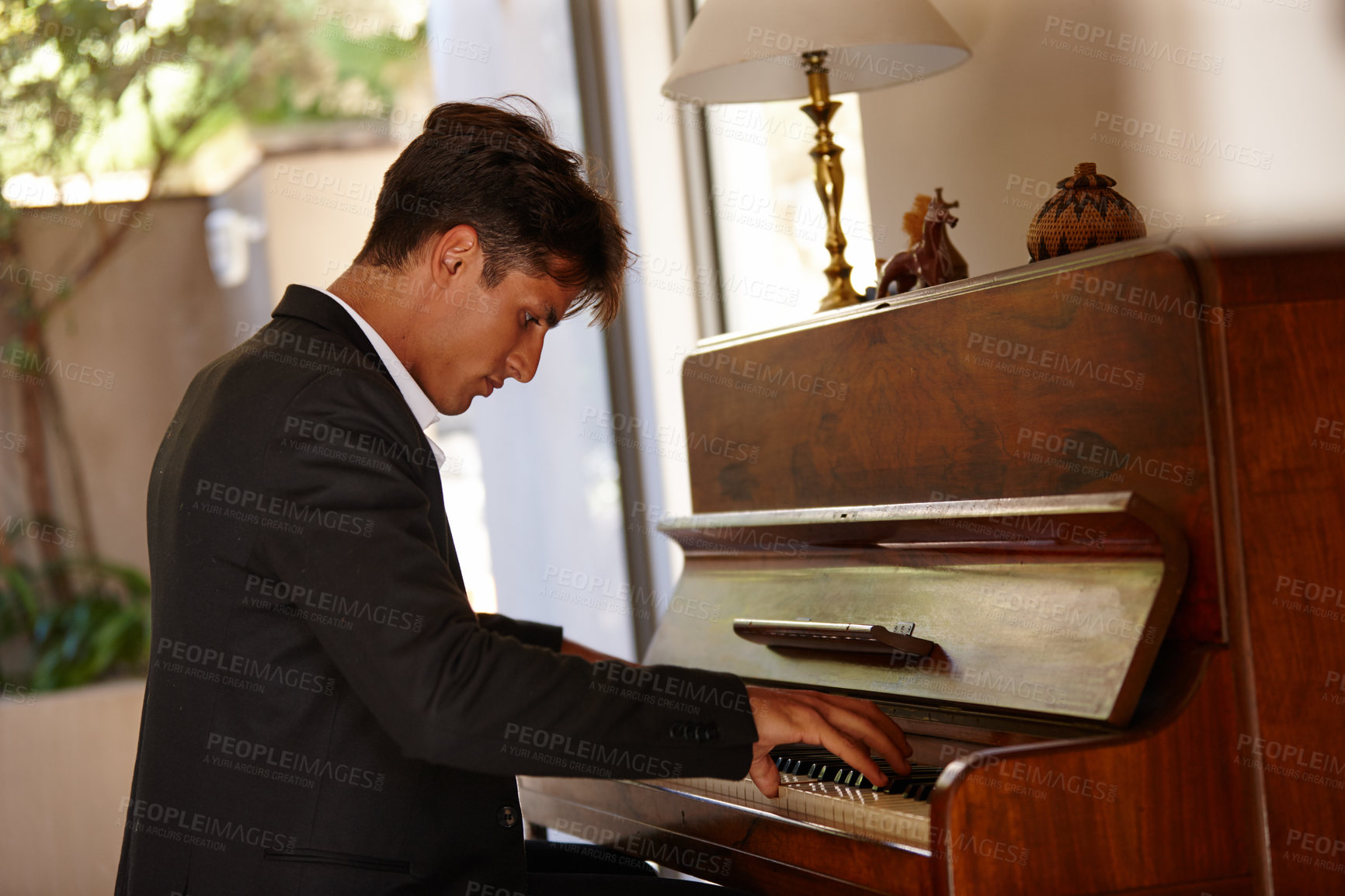 Buy stock photo Shot of a handsome young man playing the piano at home