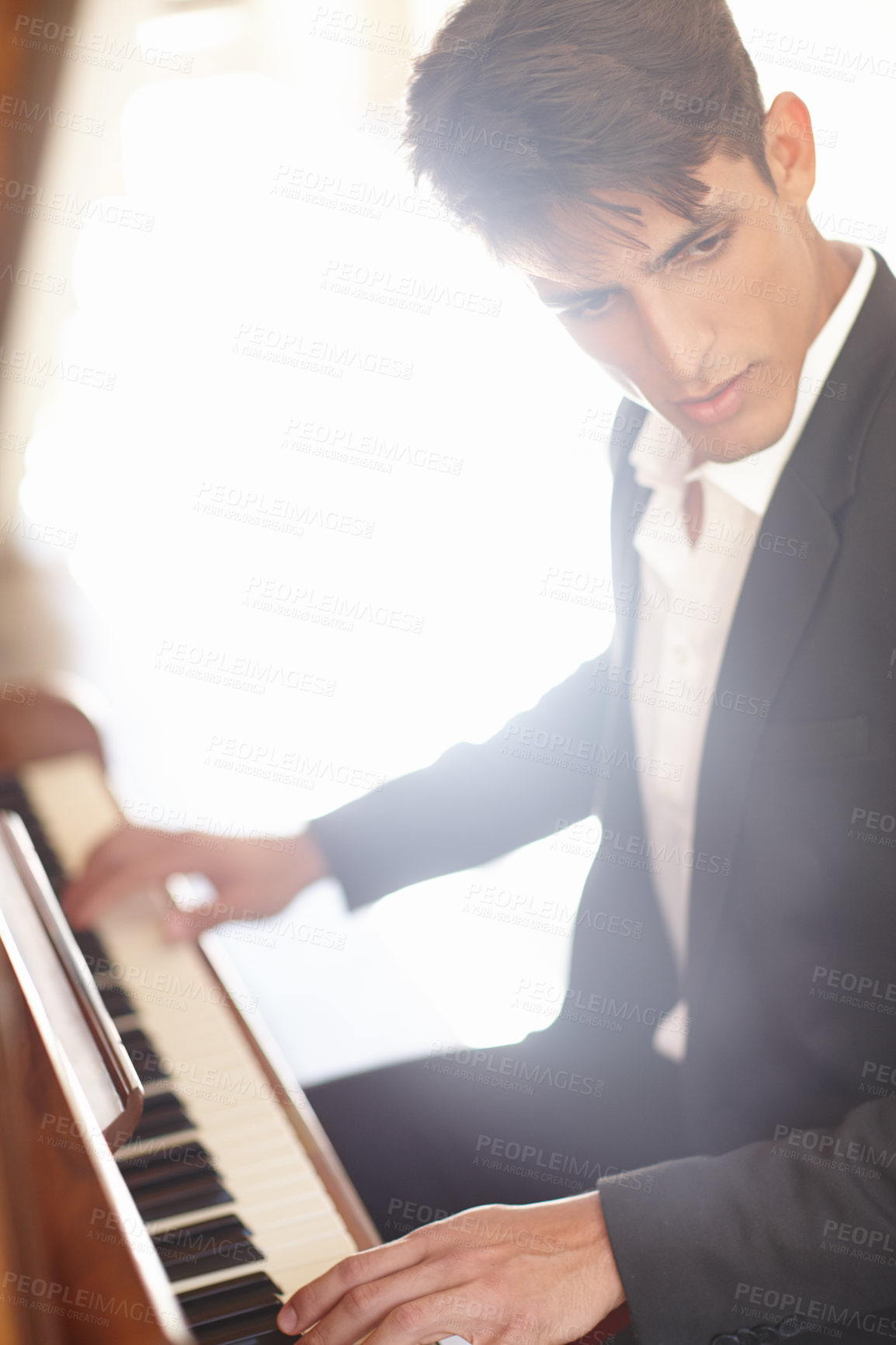 Buy stock photo Shot of a handsome young man looking inspired while playing the piano