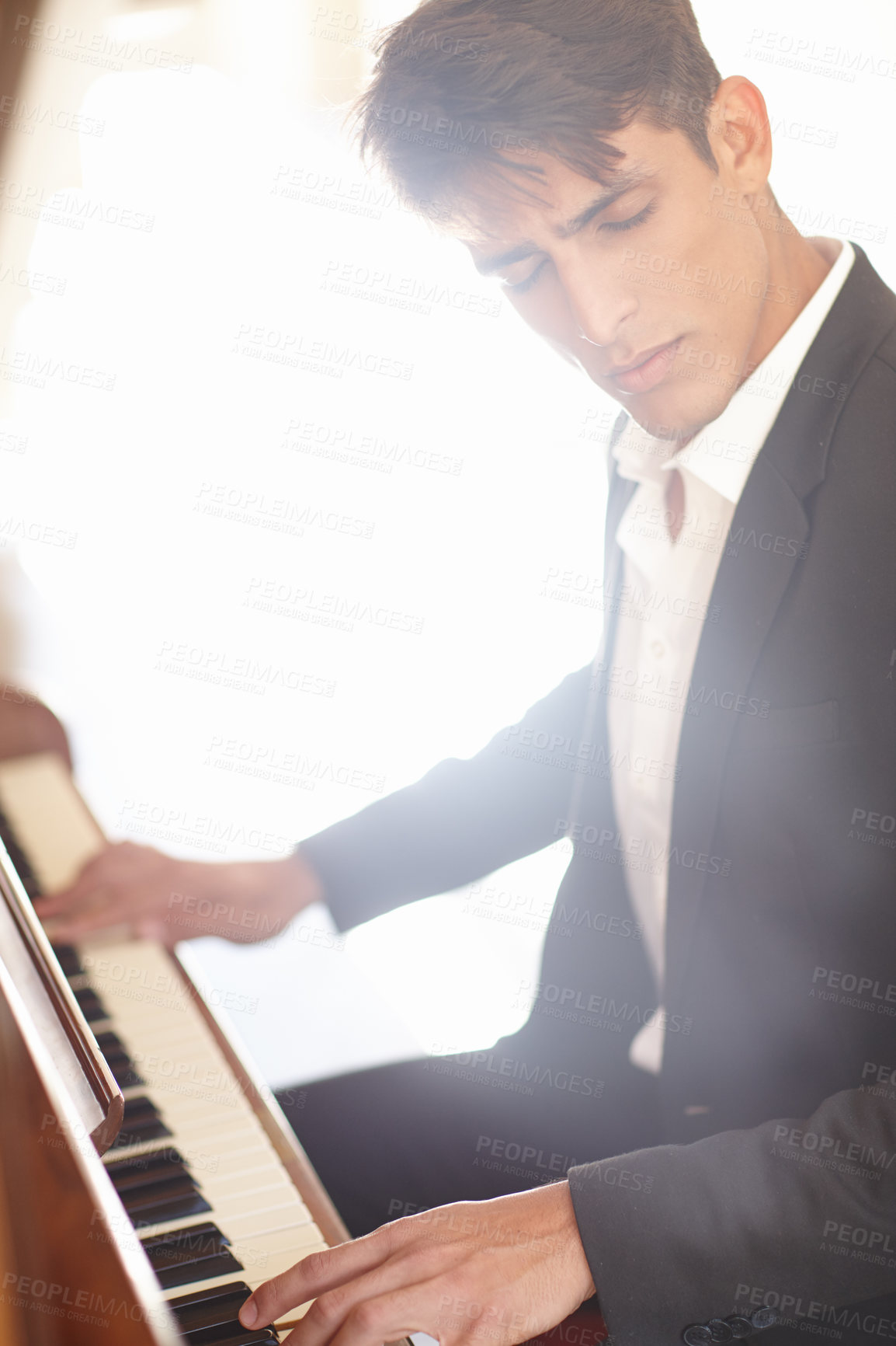 Buy stock photo Shot of a handsome young man looking inspired while playing the piano