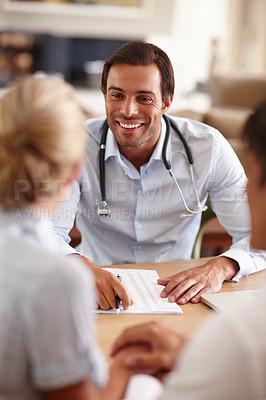 Buy stock photo Shot of a male doctor giving good news to a couple in his office