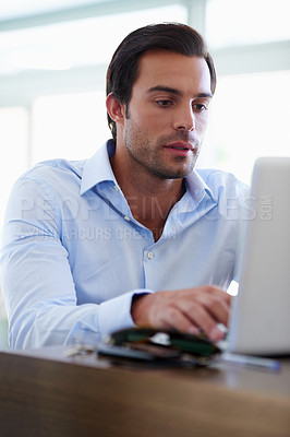 Buy stock photo Shot of a handsome businessman working on his laptop at his desk