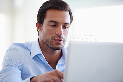 Buy stock photo Shot of a handsome businessman working on his laptop