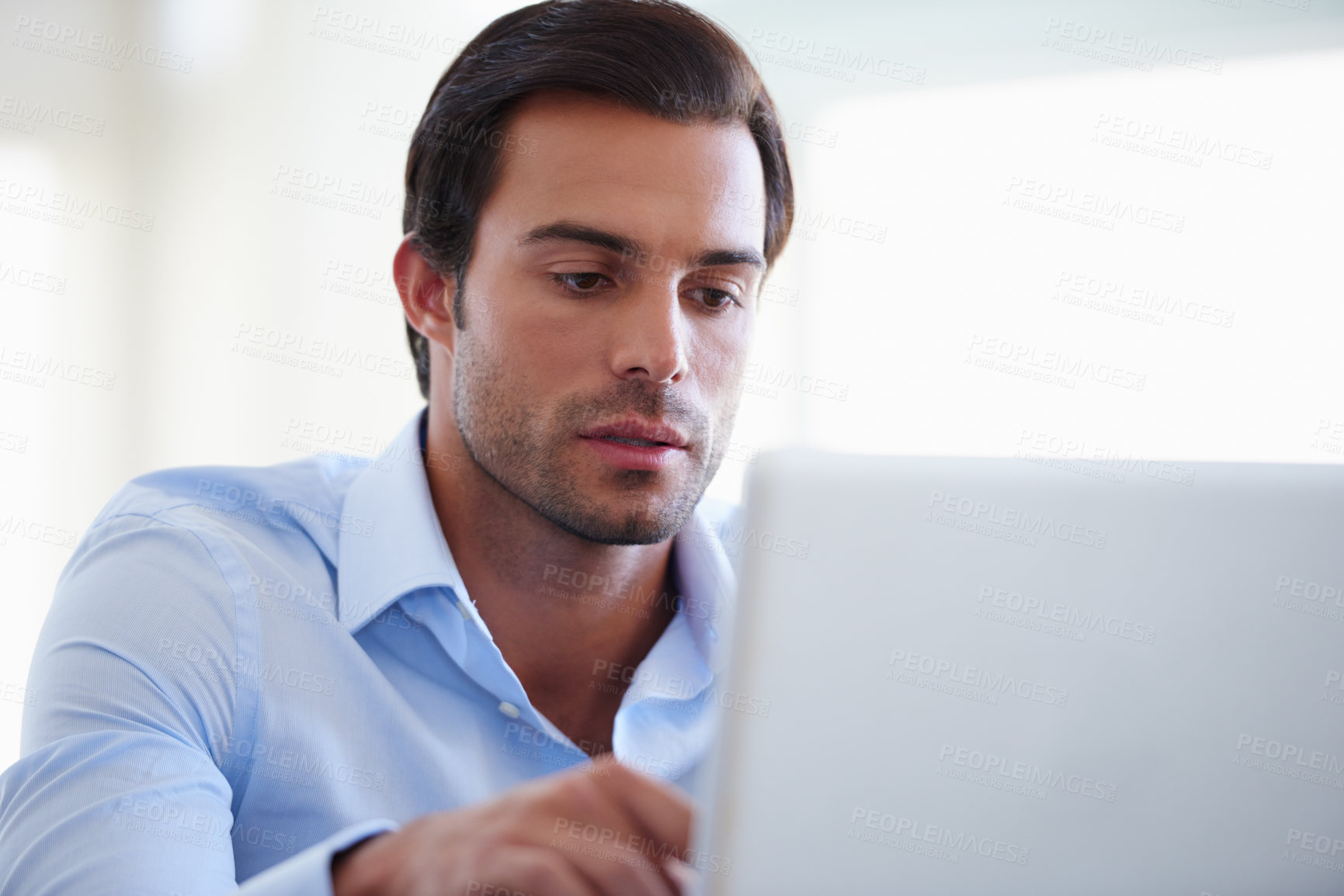 Buy stock photo Shot of a handsome businessman working on his laptop