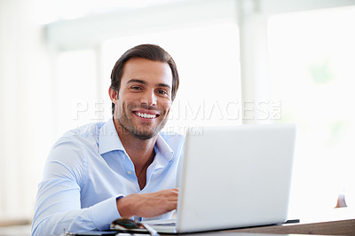 Buy stock photo Portrait of a handsome businessman using his laptop in the office