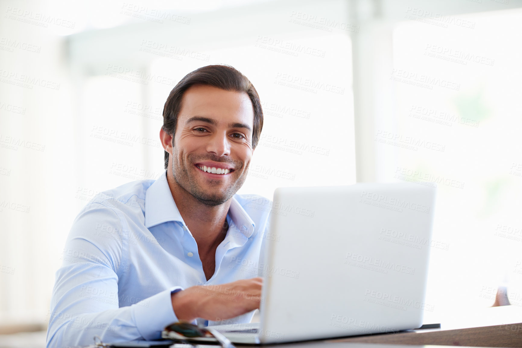 Buy stock photo Portrait of a handsome businessman using his laptop in the office