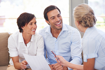 Buy stock photo Shot of a financial advisor explaining documents to a couple