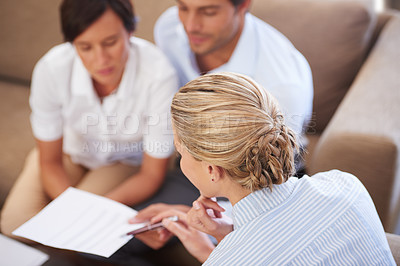 Buy stock photo Shot of a financial advisor explaining documents to a couple