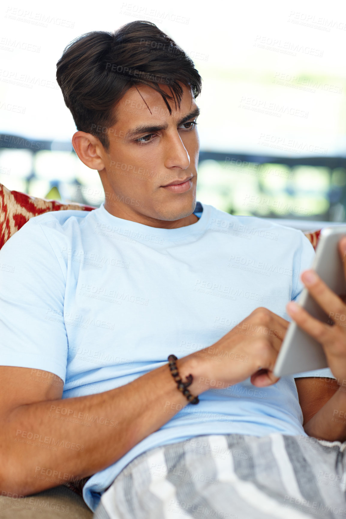 Buy stock photo Cropped shot of a young man using his digital tablet at home