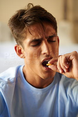 Buy stock photo Shot of a young man taking medication