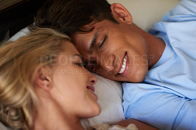 Buy stock photo Shot of a young married couple lying face to face in bed