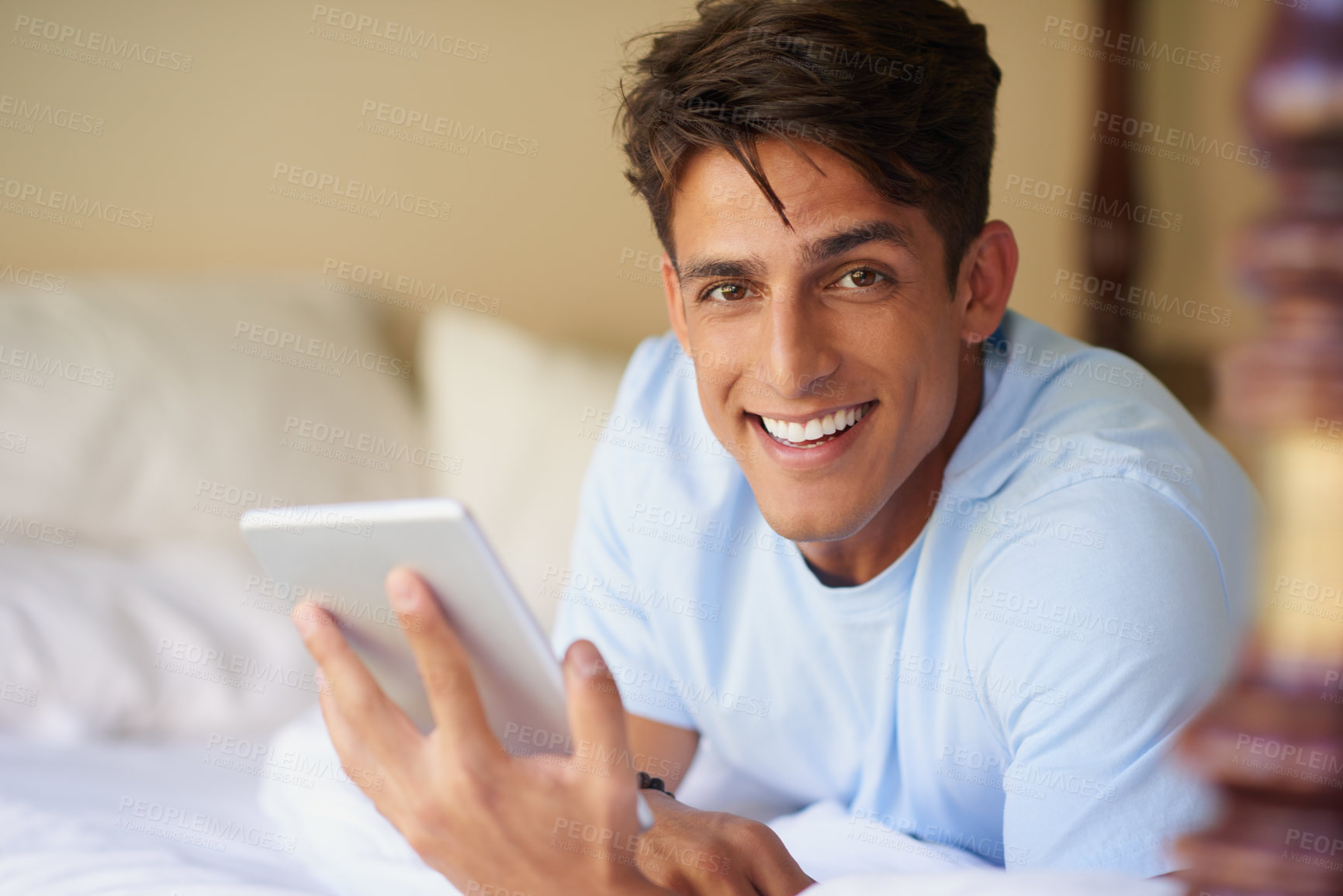 Buy stock photo Cropped shot of a handsome young man using his digital tablet at home