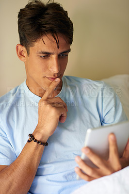 Buy stock photo Cropped shot of a handsome young man using his digital tablet at home