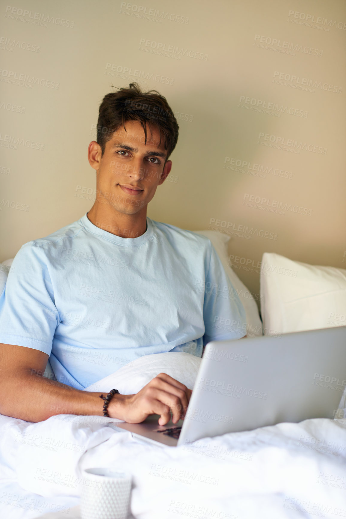 Buy stock photo A handsome young men sitting in bed with his laptop