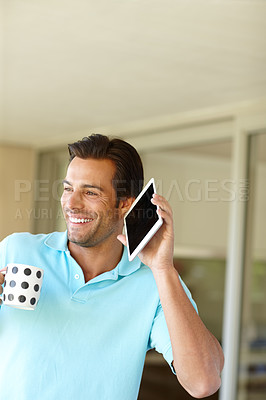 Buy stock photo Shot of a man holding his digital tablet to his ear while having coffee