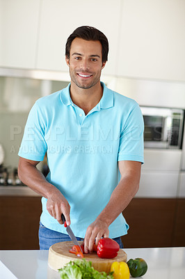 Buy stock photo Portrait of a handsome man chopping vegetables at a kitchen counter