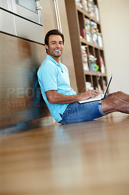 Buy stock photo Portrait of a handsome man using his laptop while sitting on the floor at home