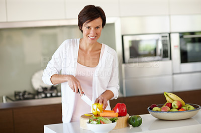 Buy stock photo Portrait of an attractive woman chopping vegetables at the kitchen counter