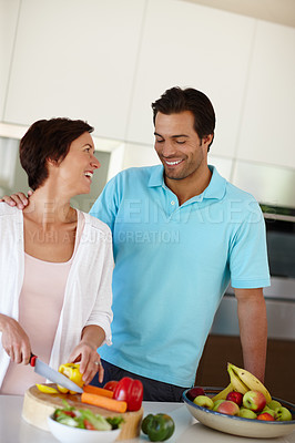 Buy stock photo Shot of a man standing beside his wife as she's chopping vegetables at the kitchen counter