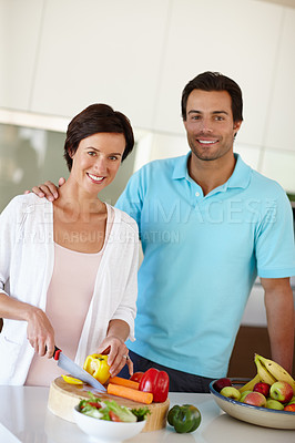 Buy stock photo Shot of a man standing beside his wife as she's chopping vegetables at the kitchen counter