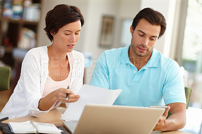 Buy stock photo Shot of a couple sitting with a laptop busy doing budget calculations