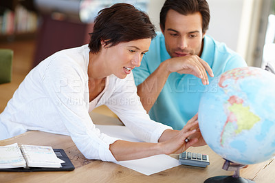 Buy stock photo Shot of a married couple looking at a world globe while planning a vacation