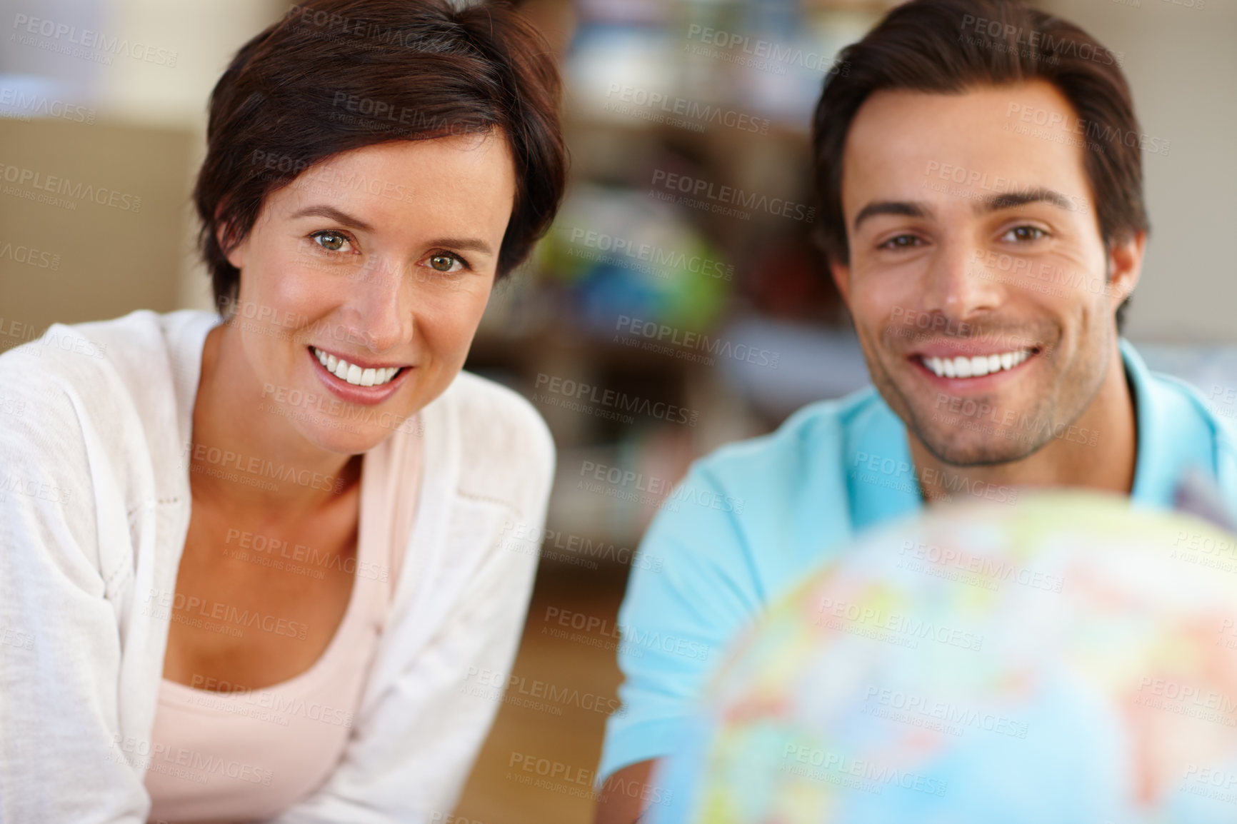 Buy stock photo Defocused shot of a couple sitting alongside a globe of the world