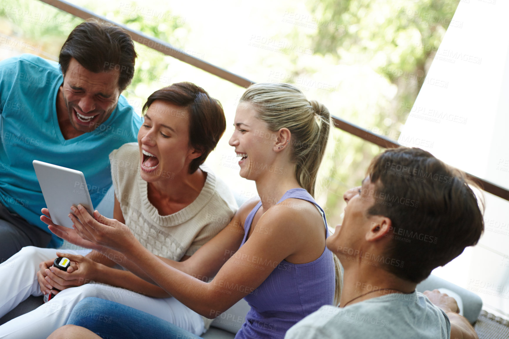 Buy stock photo Shot of a group of friends with a tablet laughing at something funny online