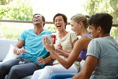 Buy stock photo Shot of a group of friends with a tablet laughing at something funny online