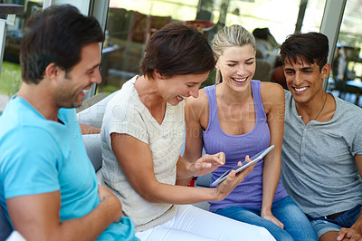 Buy stock photo Shot of a group of friends with a tablet laughing at something funny online