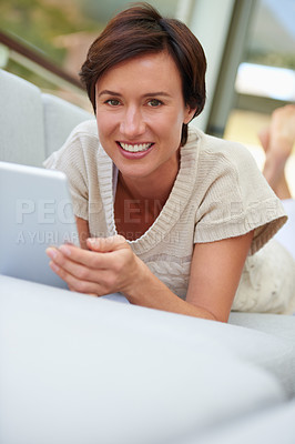 Buy stock photo Portrait of an attractive woman lying on the sofa with her digital tablet