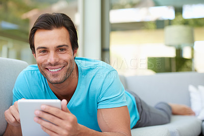 Buy stock photo Portrait of a handsome man lying on the sofa with his digital tablet