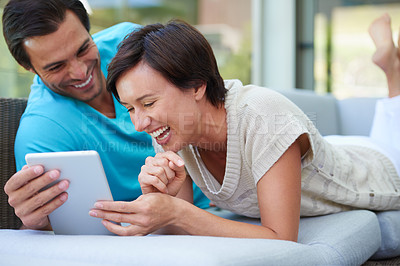 Buy stock photo Shot of a couple with a tablet laughing at something funny online