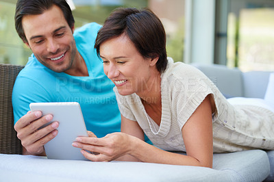 Buy stock photo Shot of a couple with a tablet laughing at something funny online