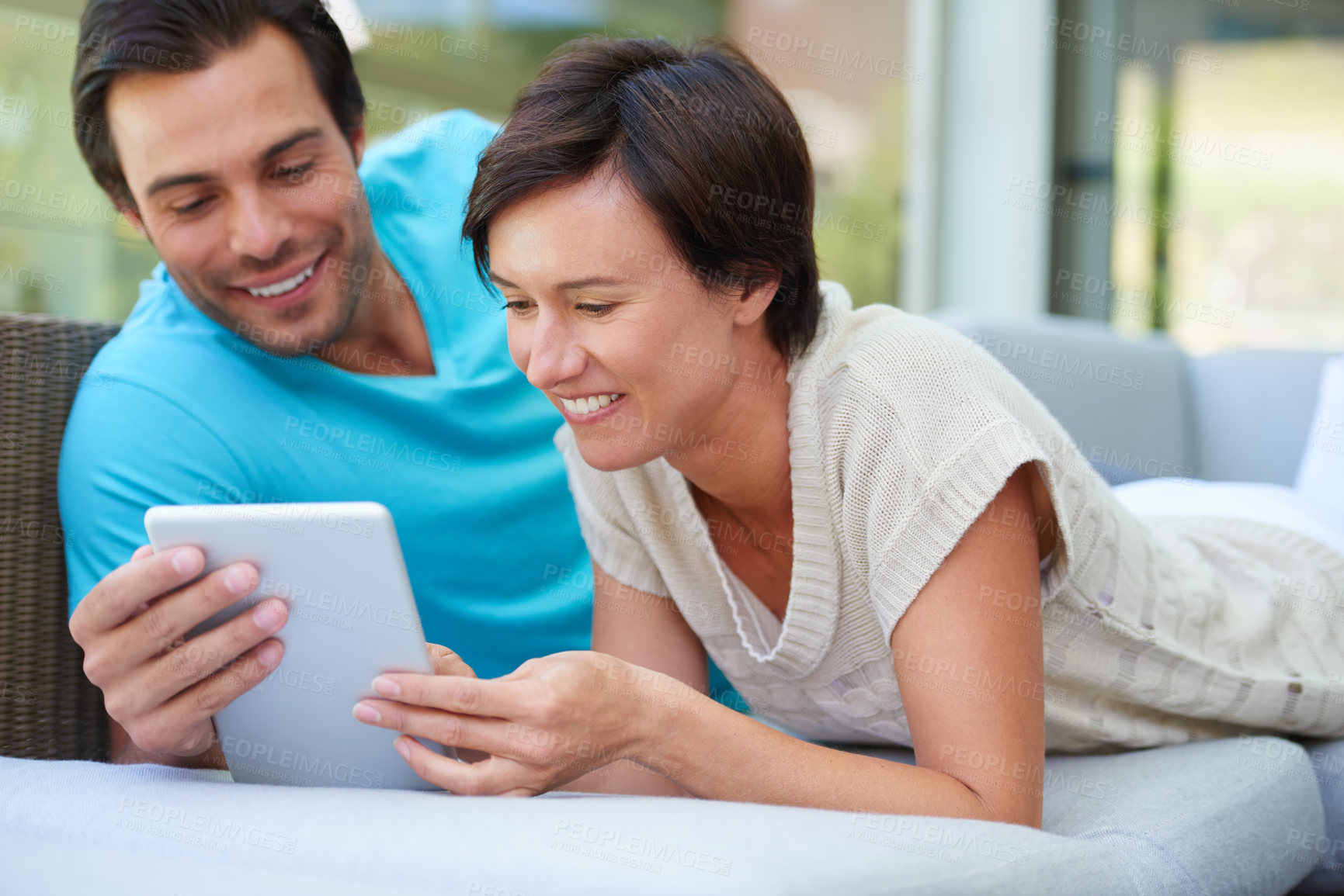 Buy stock photo Shot of a couple with a tablet laughing at something funny online