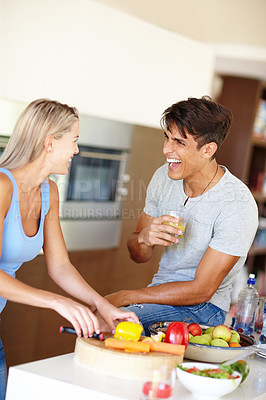 Buy stock photo Shot of a young man laughing while chatting with his girlfriend in the kitchen
