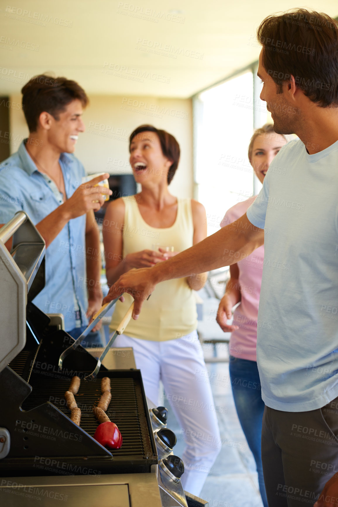 Buy stock photo Shot of a group of young friends enjoying a barbeque