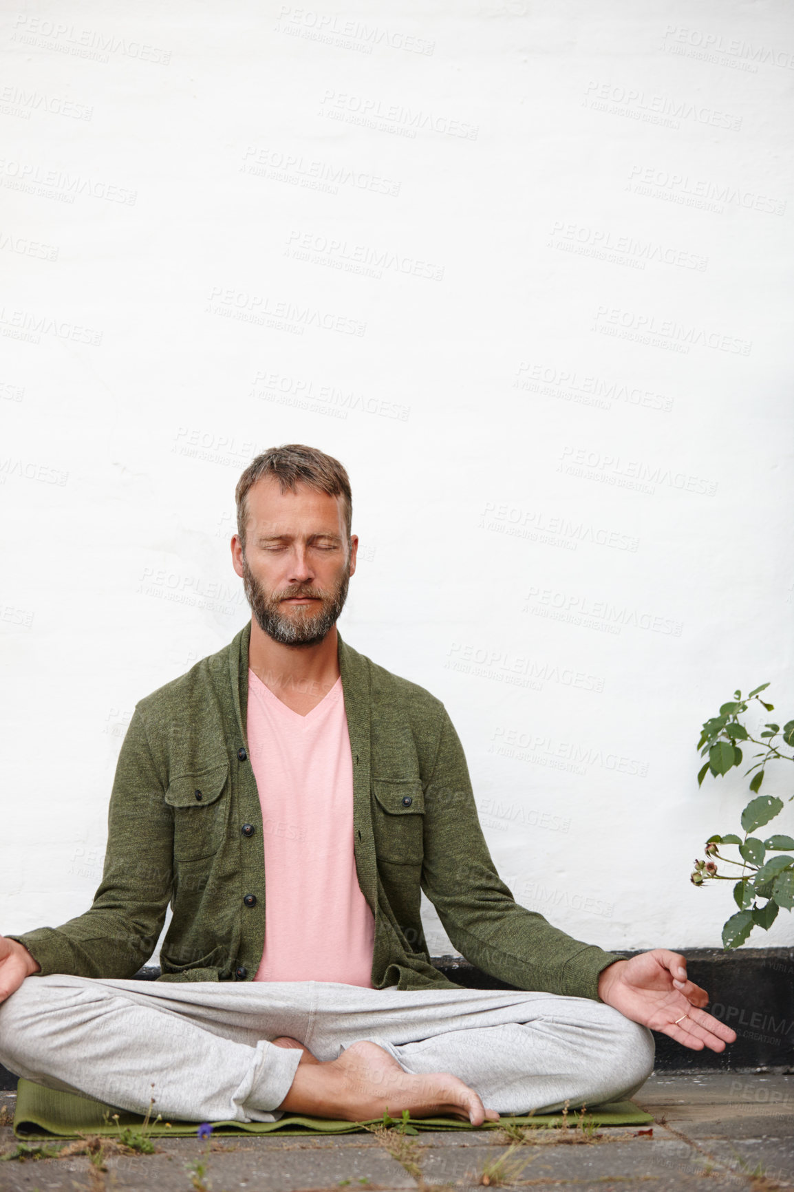 Buy stock photo Shot of a handsome mature man meditating in the lotus position in a courtyard