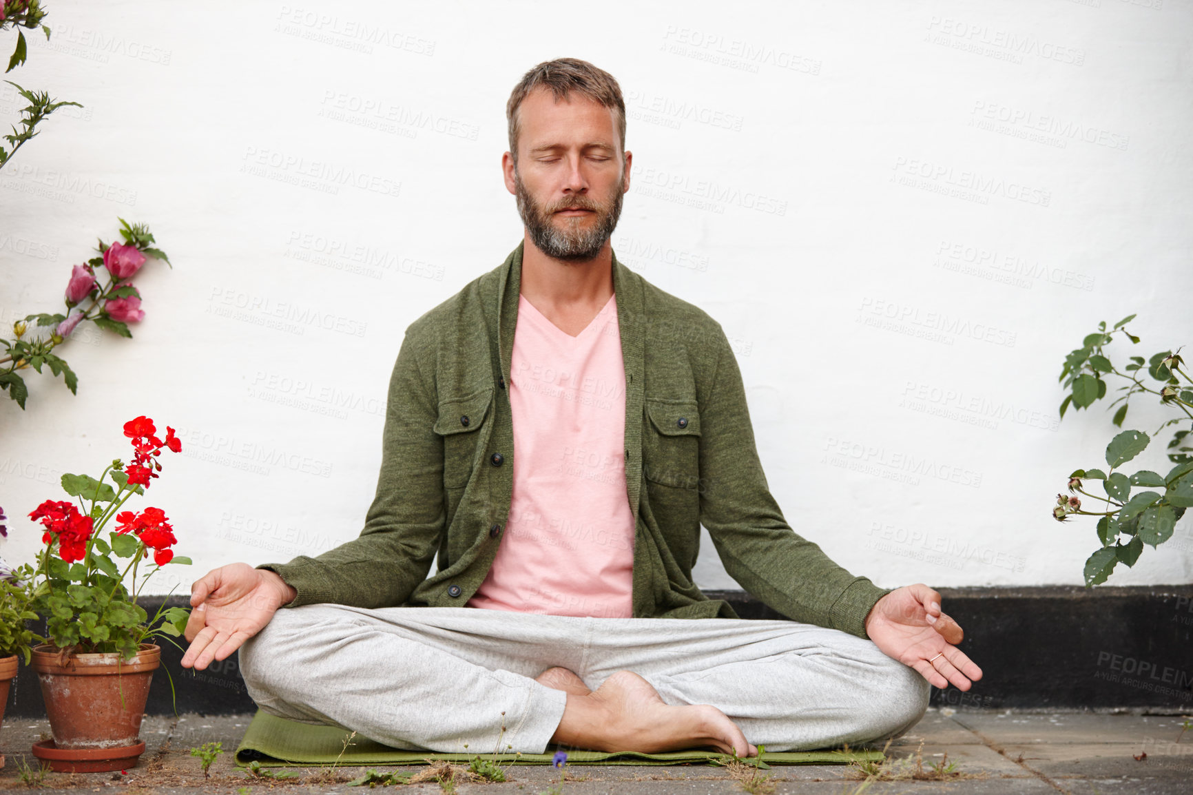 Buy stock photo Shot of a handsome mature man meditating in the lotus position in a courtyard